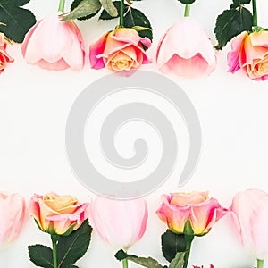 Floral frame made of roses and tulips flowers and green leaves on white background. Flat lay, top view. Flower background