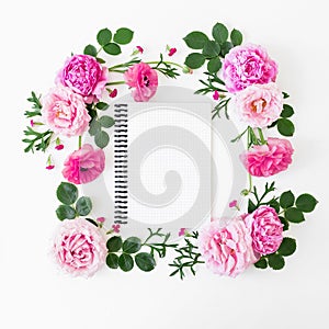 Floral frame of pastel pink roses, peonies and notebook on white background. Flat lay, top view. Spring time composition