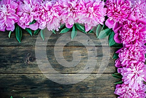 Floral frame with pink peonies flowers on wood background. Selective focus, place for text, top view