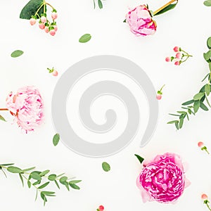 Floral frame of pink peonies, hypericum and eucalyptus leaves on white background. Flat lay, top view