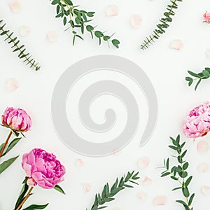 Floral frame of pink peonies, roses and eucalyptus branches on white. Flat lay