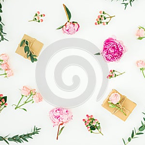 Floral frame of pink peonies, roses, hypericum and eucalyptus with clipboard and gifts box on white background. Flat lay, top view