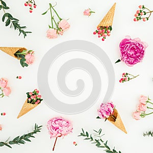 Floral frame of pink peonies, roses petals, eucalyptus and waffle cones on white background. Flat lay, top view