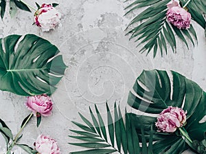 Floral frame with pink peonies and tropical leaves.