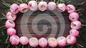 Floral frame of pink peonies on wooden background, styled