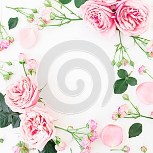Floral frame with pink roses, buds and leaves on white background. Flat lay, top view. Spring frame background