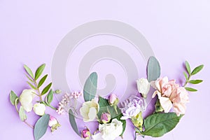 Floral frame with pink roses, white flowers, branches, leaves and petals on purple background. Flat lay, top view