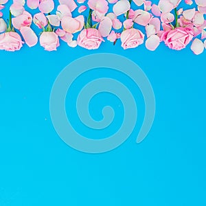 Floral frame of roses buds and petals on blue background. Flat lay, Top view. Valentines day holiday