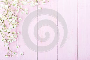 Floral frame of small  white flowers  Gypsophila  on light pink wooden background. Vintage style image. Flat lay