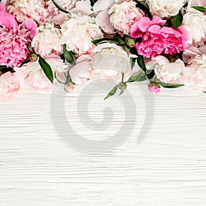 Floral frame wreath made of pink and beige peonies flower buds, eucalyptus branches and leaves isolated on white wooden