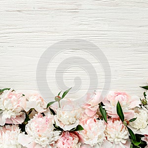 Floral frame wreath made of pink and beige peonies flower buds, eucalyptus branches and leaves isolated on white wooden