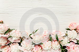 Floral frame wreath made of pink and beige peonies flower buds, eucalyptus branches and leaves isolated on white wooden