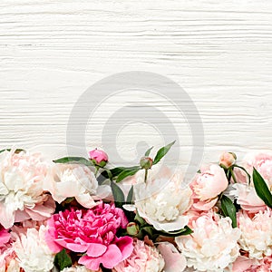 Floral frame wreath made of pink and beige peonies flower buds, eucalyptus branches and leaves isolated on white wooden