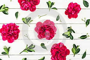 Floral pattern composition of red peony flowers and leaves on white rustic background. Flat lay
