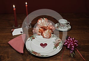 Floral pattern fine china dinnerware with matching plate, cup and saucer. bouquet of orange and white roses, pink napkin, silverwa