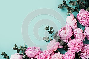 Floral pattern, frame made of pink peonies, eucalyptus flowers on pastel blue background. Flat lay, top view. Copy space. Wedding