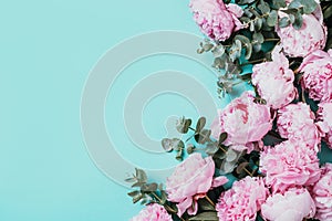 Floral pattern, frame made of pink peonies, eucalyptus flowers on pastel blue background. Flat lay, top view. Copy space. Wedding