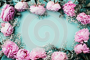 Floral pattern, frame made of pink peonies, white gypsophila flowers, eucalyptus on blue background. Flat lay, top view. Copy
