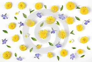 Floral pattern made of yellow dandelion, lilac flowers and leaves isolated on white background. Flat lay.