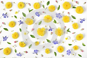 Floral pattern made of yellow dandelion, lilac flowers, pink buds and green leaves isolated on white background. Flat lay.