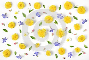 Floral pattern made of yellow dandelion, lilac flowers, pink buds and green leaves isolated on white background. Flat lay.