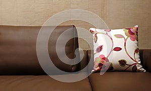 Floral pillow on a brown leather couch - home interiors