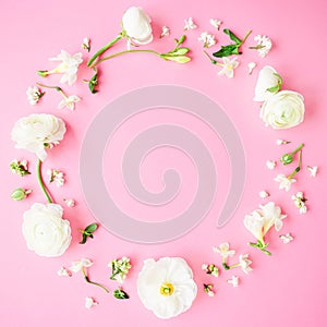 Floral round frame made of white flowers, buds and petals on pink background. Flat lay, top view. Pastel background.