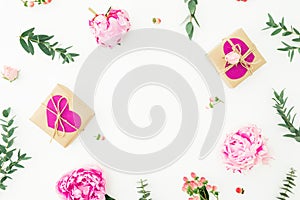 Floral round frame of pink peonies, roses, hypericum and eucalyptus branches and gifts on white background. Love composition