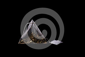 Floral tea bag with white label isolated on black background. Tea pyramid close up