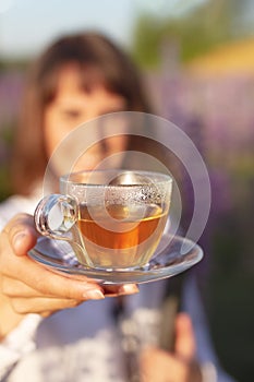 floral tea in hand of woman in field of lavender