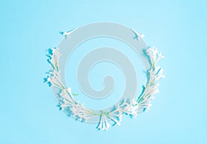 Floral wreath of white common lilac flowers on a blue background. Top view, flat lay. copy space.