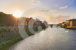 Florence or Firenze, Ponte Santa Trinita medieval Bridge landmark on Arno river and a boat, sunset landscape. Ponte Vecchio on the