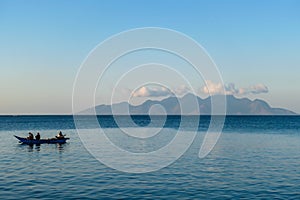 Flores/Indonesia 20290808: A fishermen`s boat crossing a calm sea near Maumere, Indonesia There are three men in one small, blue photo