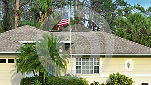 Florida suburban home with USA national flag waving on wind in front yard. American stars and stripes spangled banner as