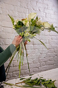 The florist creates a floral arrangement of roses, lilacs, callas, carnations, hydrangeas, brasica, alstroemeria, ornithogalum,