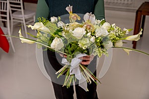 The florist creates a floral arrangement of roses, lilacs, callas, carnations, hydrangeas, brasica, alstroemeria, ornithogalum,