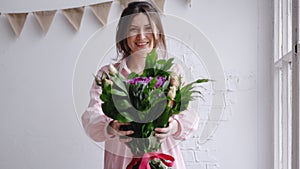 Florist girl looks at the camera and shows the bouquet. Portrait in a flower shop
