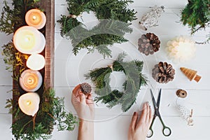 Florist hands making rustic christmas wreath with fir branches,flat lay