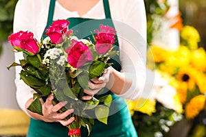 Florist hands showing red roses bouquet flowers
