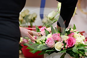 Florist make a flower box with pink and white roses, white roses in a tank on a background