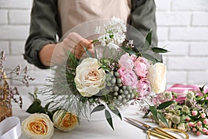 Florist making beautiful bouquet at white table, closeup photo