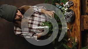 Florist making Christmas flower arrangement. Vertical video. Floral workshop.