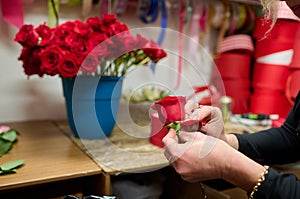 Florist making flower box with red roses on the table, red roses in the tank in the background