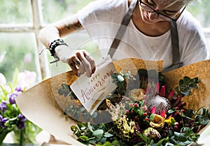 Florist Making Fresh Flowers Bouquet Arrangement with Happy Anniversary Card