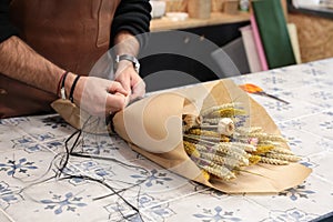 Florist packs a bouquet of beautiful dried flowers plants - chrysanthemums, lavender, poppies, wheat spikelets in the greek flower