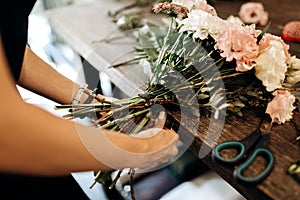 Florist ties a ribbon on the stems of flowers in flower shop