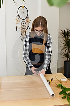 florist woman cutting paper on table with plants.