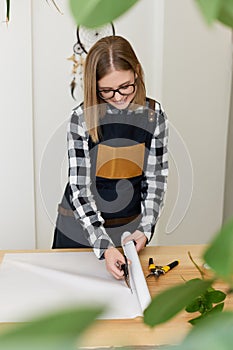 florist woman cutting paper on table with plants.