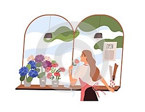 Florist woman smelling fresh flower at flora shop. Vendor in retail store with blooming plants in pots and vases. Seller