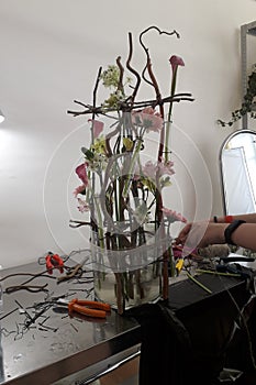 Florist at work. Creating a flower arrangement in a floral vessel. Setting flowers in test tubes.